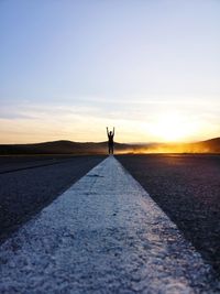 Man standing on road against sky during sunset