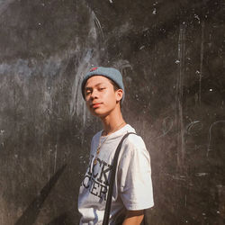 Full length of young man looking away against wall