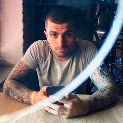 Portrait of young man using mobile phone while sitting on table