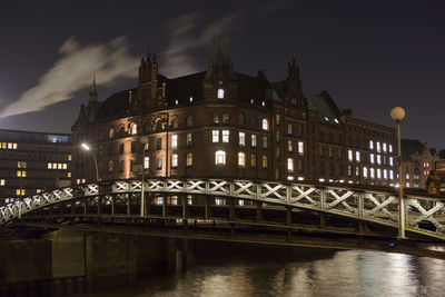 Illuminated bridge over river at night