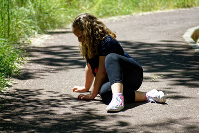 Rear view of woman sitting on road