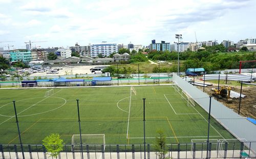 High angle view of soccer field by buildings against sky