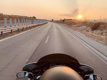 Man riding bicycle on road against sky during sunset