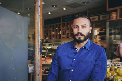 Portrait of confident sales clerk standing at store entrance