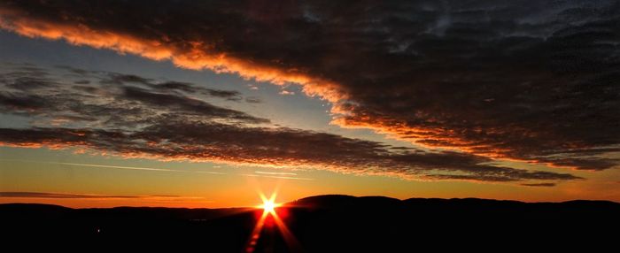 Silhouette landscape against dramatic sky during sunset