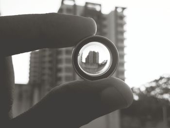 Close-up of hand holding camera against sky