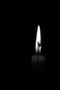 Close-up of illuminated candle over black background