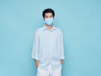 Portrait of young man standing against blue background