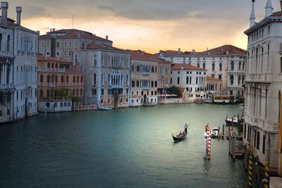 Boats in canal amidst buildings in city against sky