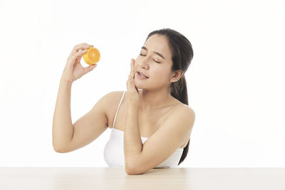 Young woman holding apple against white background