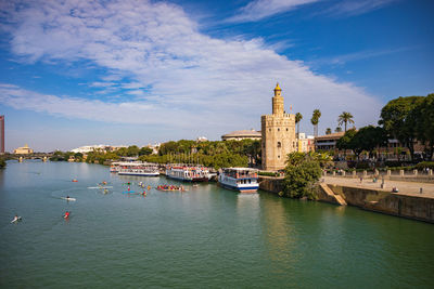 Boats in canal amidst buildings in city against sky