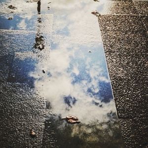 Reflection of cloudy sky in puddle