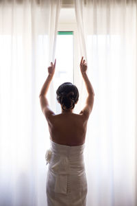 Rear view of bride opening curtain