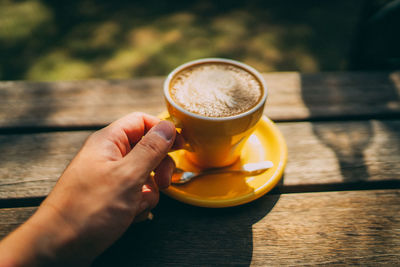 Cropped hand of woman holding coffee on table