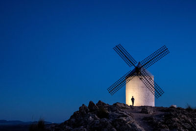 Traditional windmill on landscape against blue sky