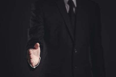 Midsection of person standing against black background