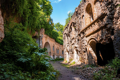 Footpath through old abandoned fort surrounded by green plants on sunny day