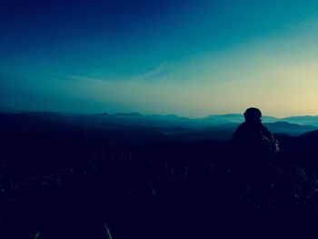 Rear view of silhouette man on landscape against clear sky