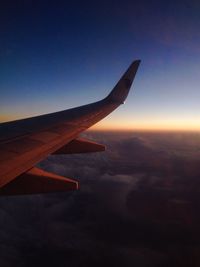 Airplane flying in sky at sunset