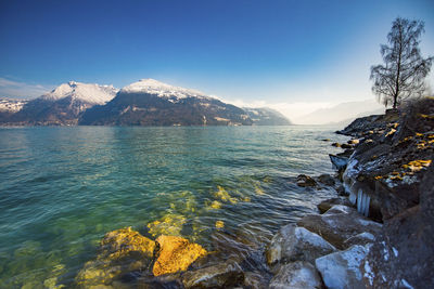 Scenic view of sea and mountains against blue sky