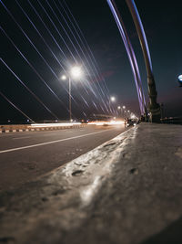 Illuminated bridge over road against sky at night