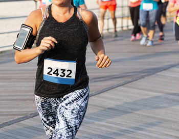 Midsection of woman using smart phone on footpath