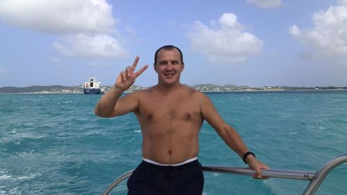 Portrait of shirtless man in sea against sky
