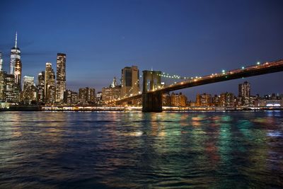 Illuminated cityscape by east river at night