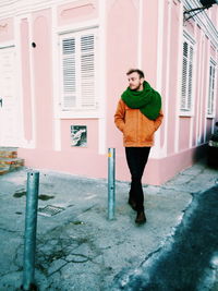 Full length of young man standing against house