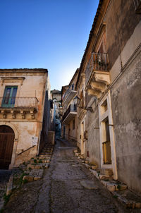 Narrow alley amidst old buildings in town against clear sky