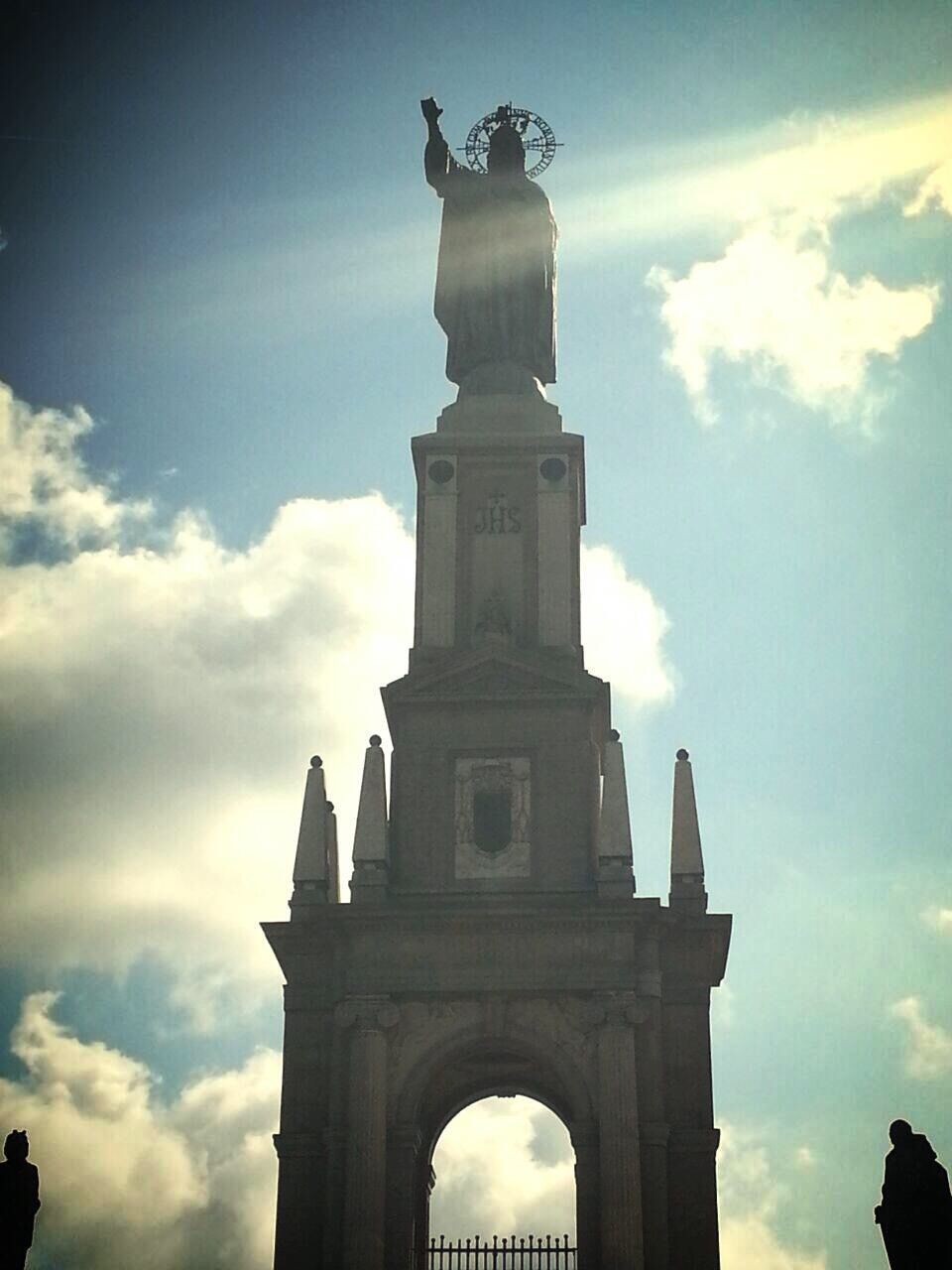 low angle view, architecture, sky, built structure, history, statue, building exterior, famous place, cloud - sky, sculpture, human representation, arch, travel destinations, architectural column, tourism, art and craft, travel, cloud, international landmark, capital cities