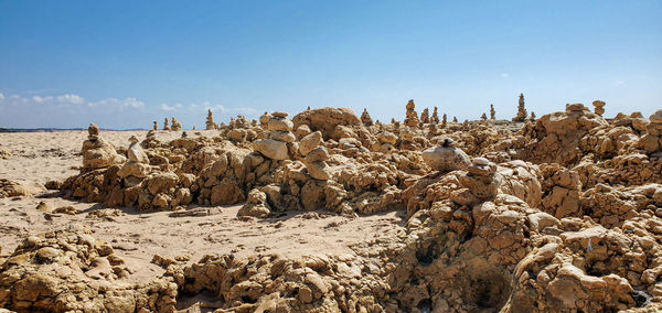 View of rocks on beach against clear blue sky