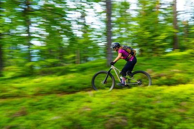 A young woman riding a mountain bike on a singletrail in the austrian alps near klagenfurt, austria.