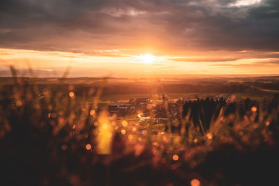 Aerial view of illuminated city against sky during sunset