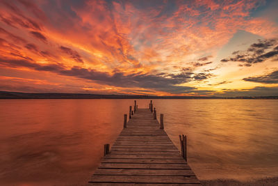 Pier over lake against sky during sunset