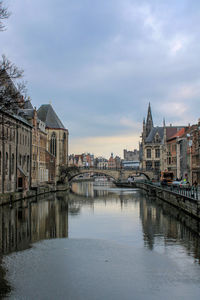 Buildings by river against sky in city