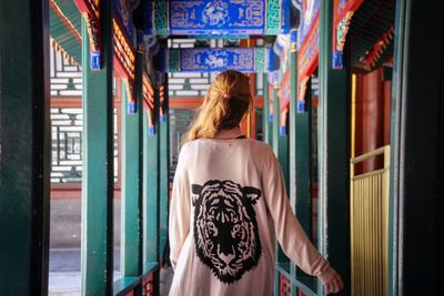 Rear view of woman walking in corridor of temple