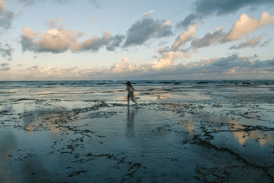 Silhouette person standing on beach against sky during sunset