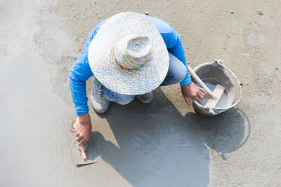 High angle view of man plastering footpath with trowel masonry