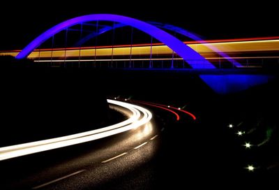 Light trails on bridge over road at night