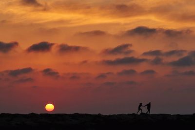 Silhouette person standing against orange sky