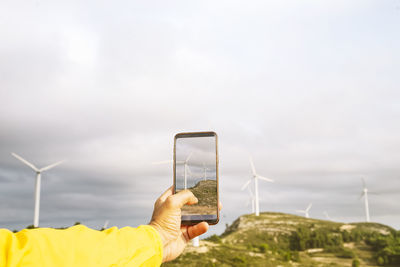 Man's hands take photo of windmills on the mountain