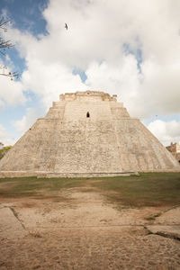 Castle on field against cloudy sky