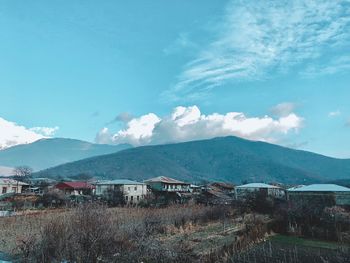 Scenic view of buildings and mountains against blue sky