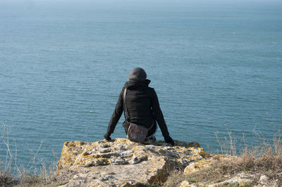 Rear view of man standing on rock against sea