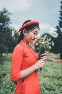 Side view of woman holding red flower