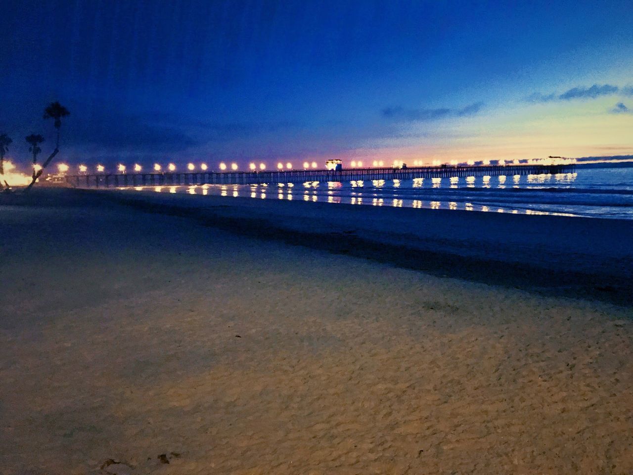 PIER ON BEACH AGAINST SKY AT NIGHT