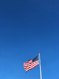 Low angle view of american flag against clear blue sky