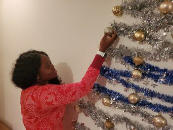 Side view of woman decorating wall at home