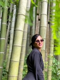 Portrait of smiling woman standing on tree trunk